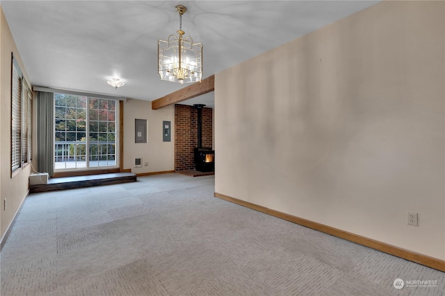 carpeted empty room with baseboards, a wood stove, a chandelier, and visible vents