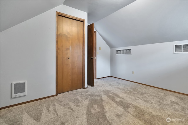 additional living space featuring light carpet, lofted ceiling, and heating unit