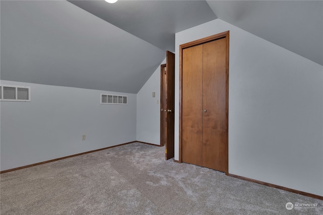 additional living space featuring light carpet and vaulted ceiling