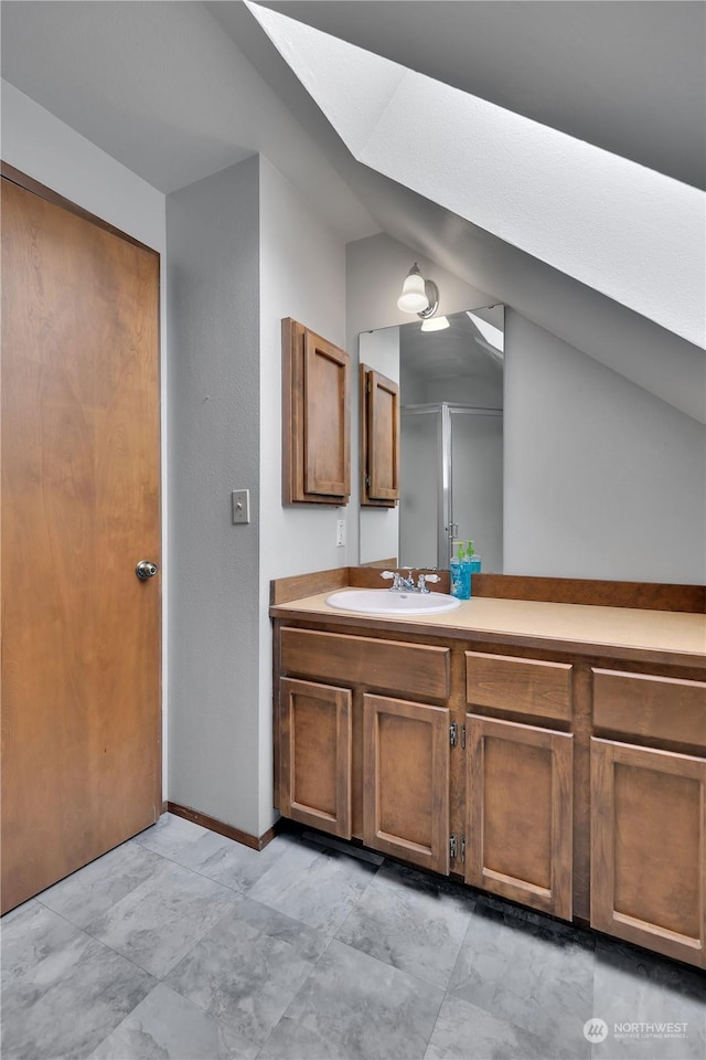 bathroom featuring baseboards, lofted ceiling with skylight, and vanity