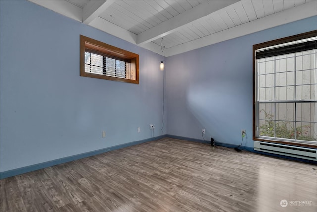 empty room with baseboards, baseboard heating, beamed ceiling, and wood finished floors