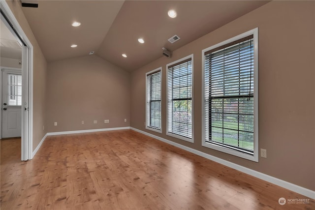 empty room featuring light wood-type flooring, recessed lighting, baseboards, and vaulted ceiling