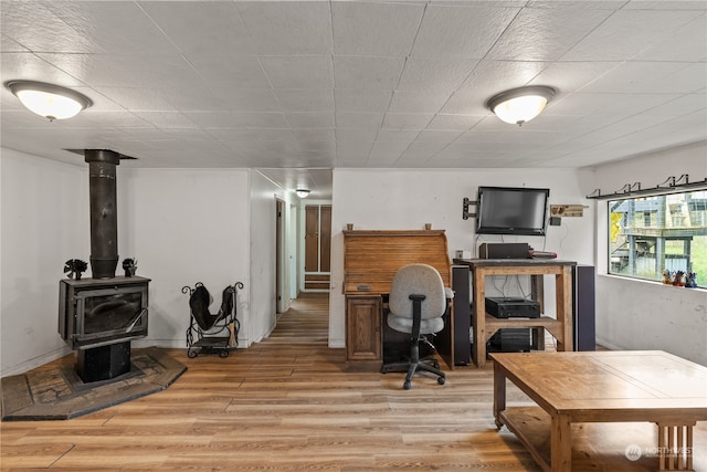 home office featuring a wood stove and wood-type flooring