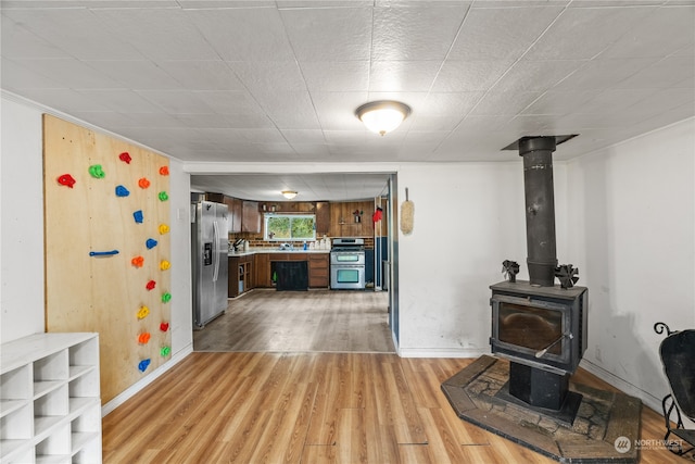 kitchen featuring light hardwood / wood-style flooring, stainless steel appliances, and a wood stove