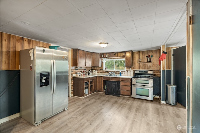 kitchen featuring tasteful backsplash, wood walls, sink, light hardwood / wood-style floors, and stainless steel appliances