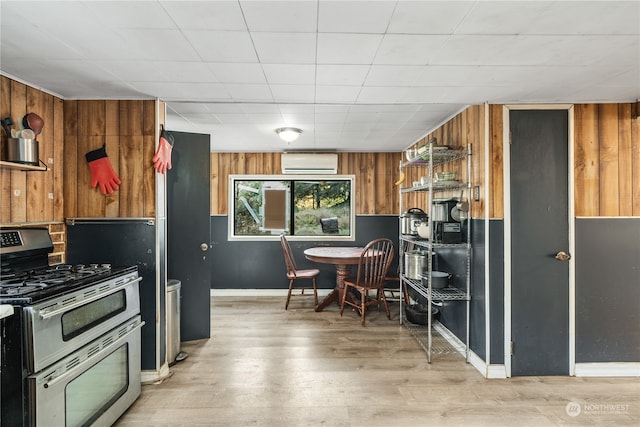 kitchen with a wall mounted AC, gas stove, light hardwood / wood-style floors, and wood walls