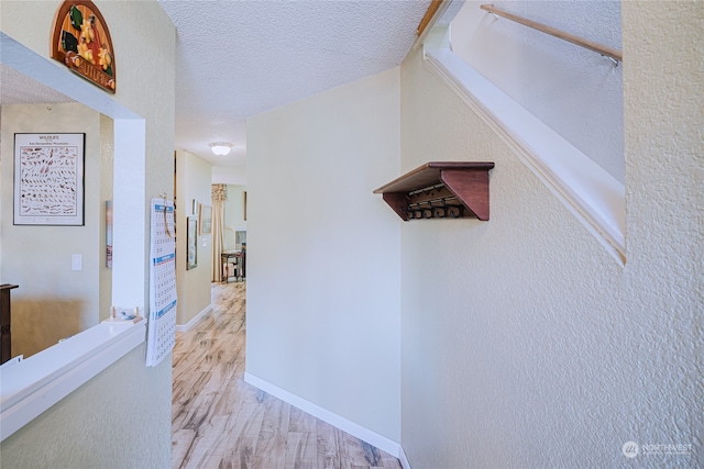 corridor with light hardwood / wood-style floors and a textured ceiling