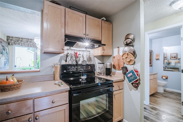 kitchen with light brown cabinets, light wood-type flooring, a textured ceiling, and black / electric stove