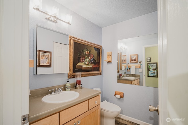 bathroom featuring hardwood / wood-style floors, vanity, a textured ceiling, and toilet