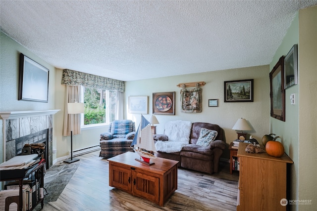 living room featuring a fireplace, light hardwood / wood-style floors, baseboard heating, and a textured ceiling