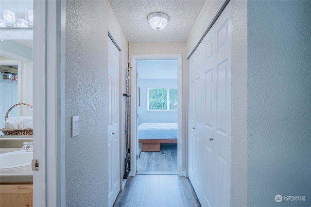 corridor with hardwood / wood-style floors, a textured ceiling, and sink