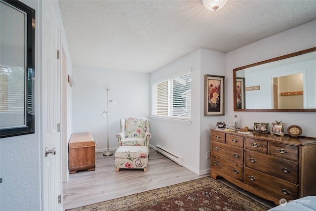 sitting room with baseboard heating, hardwood / wood-style floors, and a textured ceiling