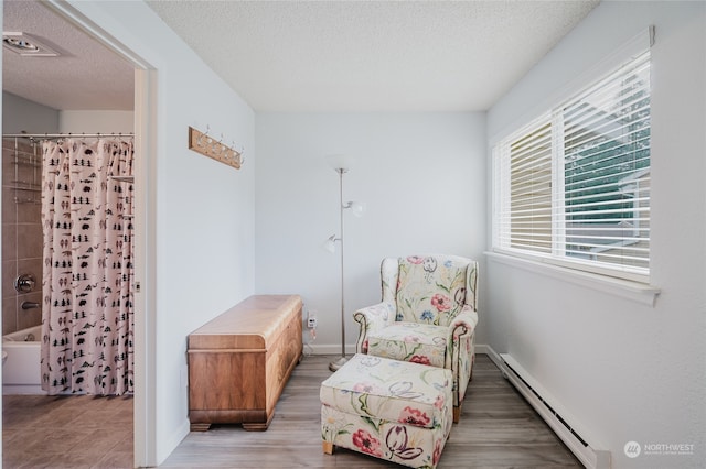 sitting room featuring baseboard heating, hardwood / wood-style floors, and a textured ceiling