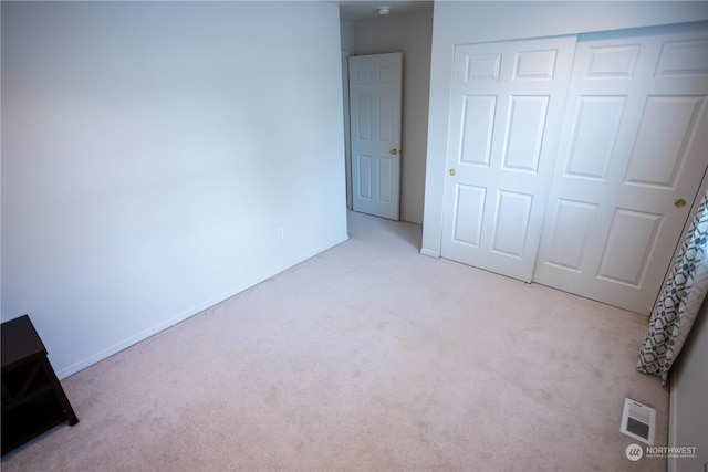 unfurnished bedroom featuring light colored carpet and a closet