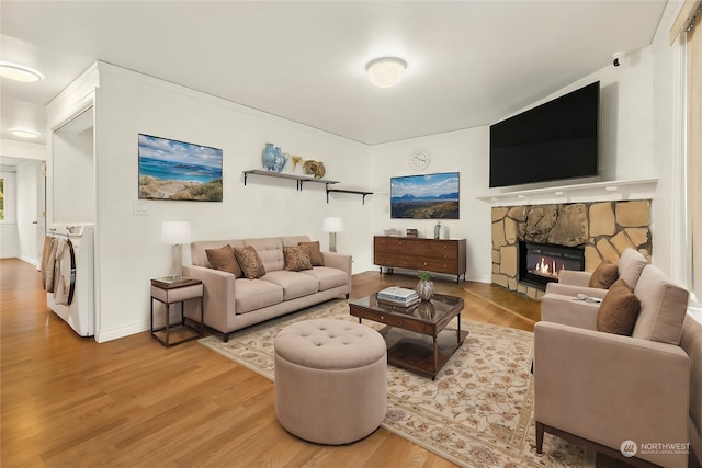 living room featuring a stone fireplace, hardwood / wood-style flooring, and washer / clothes dryer