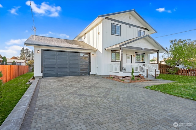 view of front of home featuring a porch, a front yard, and a garage