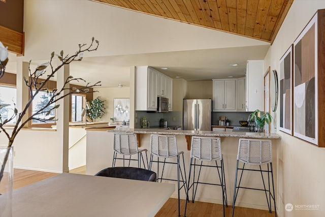 kitchen with lofted ceiling, white cabinetry, stainless steel appliances, and wooden ceiling