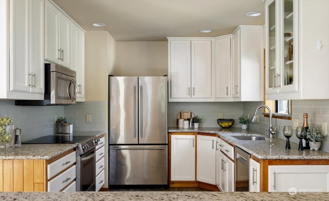 kitchen with sink, appliances with stainless steel finishes, light stone counters, and white cabinetry