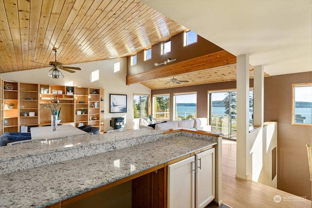 kitchen featuring lofted ceiling, light hardwood / wood-style flooring, wooden ceiling, light stone counters, and a water view