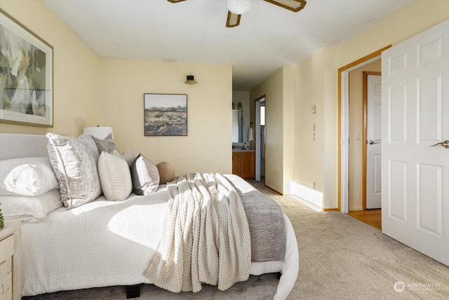 bedroom with ceiling fan, ensuite bath, and light colored carpet