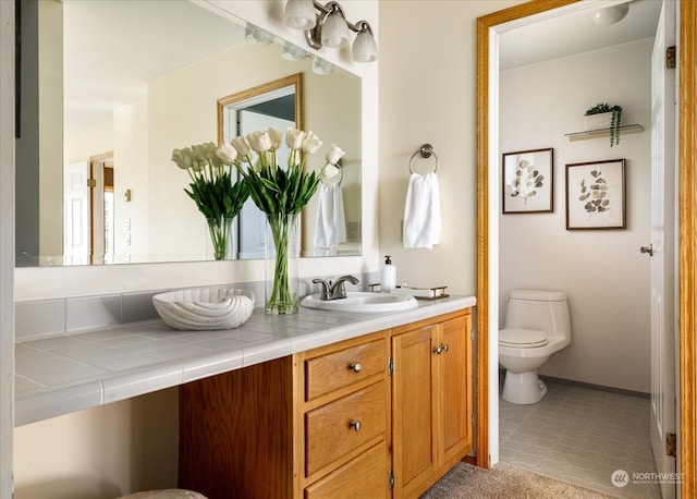 bathroom with toilet, vanity, and tile patterned floors