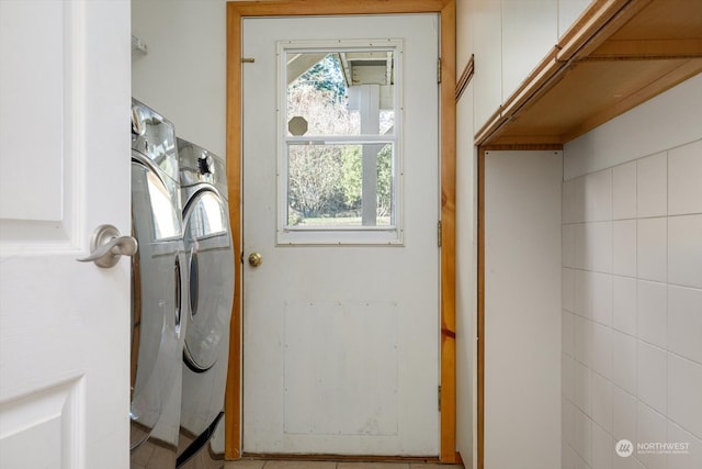 clothes washing area featuring tile walls and separate washer and dryer