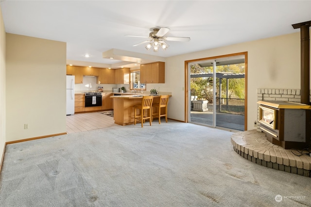 kitchen featuring a wood stove, kitchen peninsula, range, and white fridge