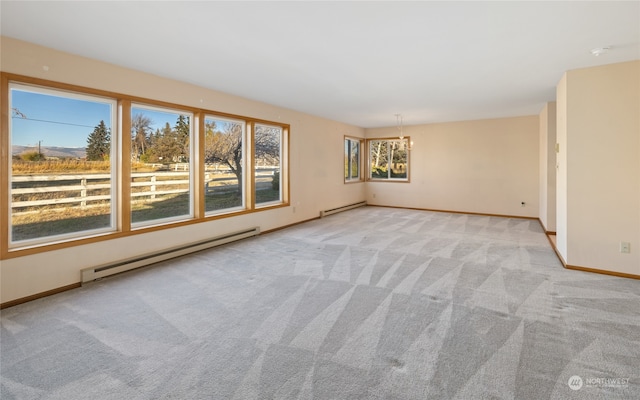 carpeted empty room with baseboard heating and a notable chandelier