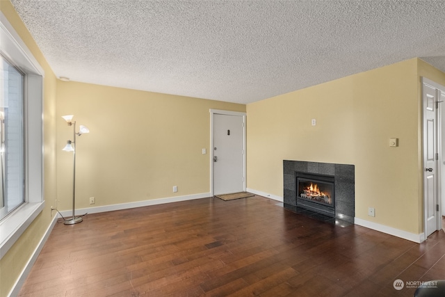 unfurnished living room with a textured ceiling, a fireplace, and dark hardwood / wood-style flooring