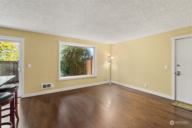 interior space with a textured ceiling, a healthy amount of sunlight, and dark hardwood / wood-style flooring