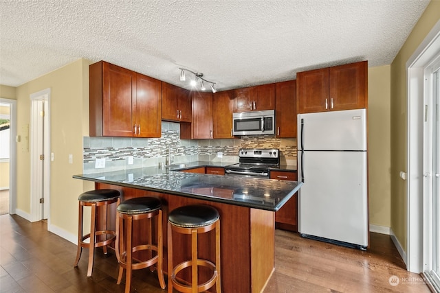 kitchen with a textured ceiling, a center island, stainless steel appliances, and light hardwood / wood-style floors