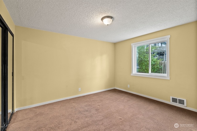 carpeted empty room with a textured ceiling