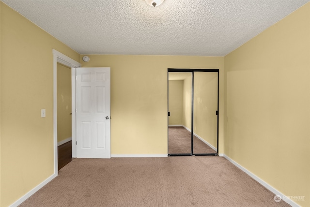 unfurnished bedroom with a closet, light carpet, and a textured ceiling