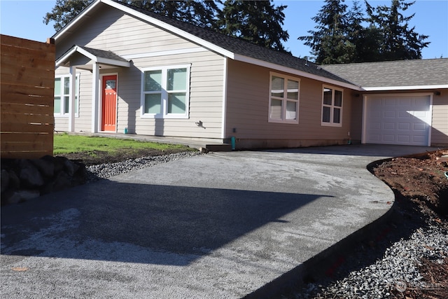 view of front facade featuring a shingled roof, driveway, and an attached garage