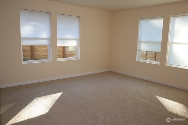 unfurnished room featuring light carpet and baseboards