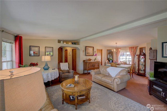 living room with carpet, a notable chandelier, lofted ceiling with beams, and a wealth of natural light