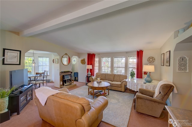 carpeted living room featuring a fireplace and vaulted ceiling with beams