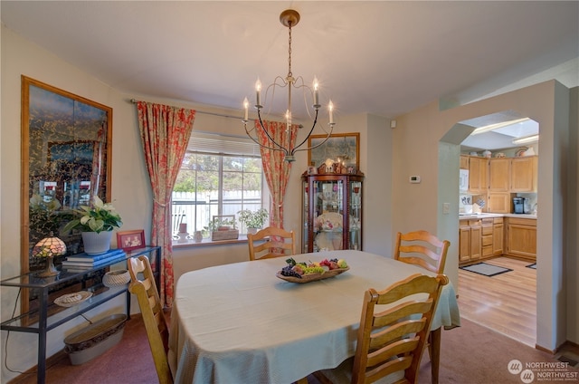 dining space with light wood-type flooring and a notable chandelier