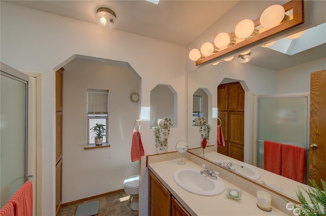 bathroom with vanity, a skylight, toilet, and walk in shower