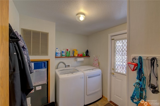 laundry room featuring a textured ceiling and washing machine and dryer