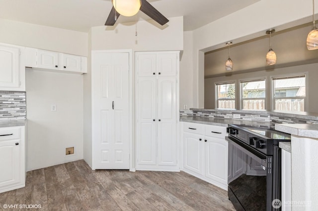 713 Main St, South Cle Elum, WA 98943 - kitchen featuring black range with electric cooktop, white cabinets, a ceiling fan, decorative backsplash, and pendant lighting