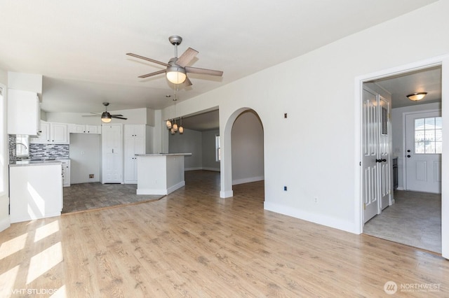 713 Main St, South Cle Elum, WA 98943 - unfurnished living room with ceiling fan, arched walkways, light wood-style floors, and baseboards