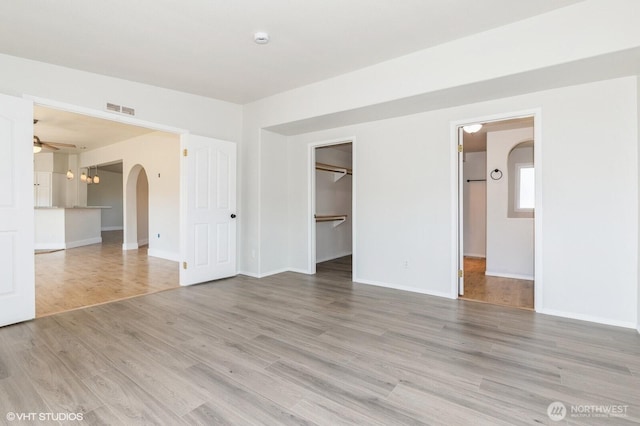 713 Main St, South Cle Elum, WA 98943 - unfurnished bedroom featuring arched walkways, light wood-style flooring, baseboards, and a walk in closet
