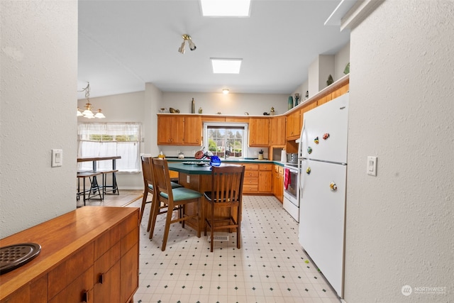 kitchen featuring lofted ceiling, sink, pendant lighting, range, and white fridge