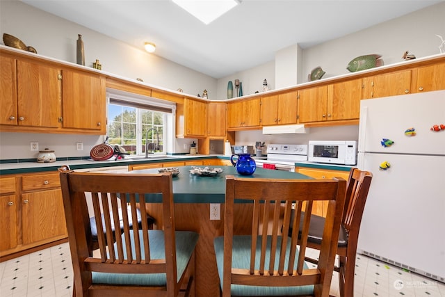 kitchen featuring sink, white appliances, and a breakfast bar