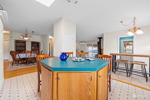 kitchen with a notable chandelier, a wood stove, light wood-type flooring, and a kitchen island