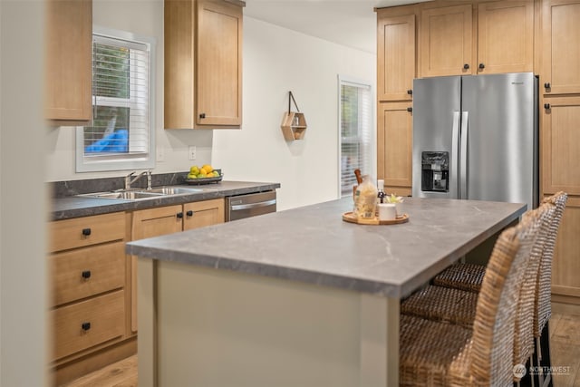 kitchen featuring appliances with stainless steel finishes, sink, light hardwood / wood-style floors, a breakfast bar area, and light brown cabinets