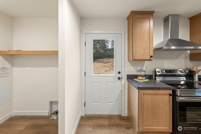 kitchen with wall chimney exhaust hood, electric range, and hardwood / wood-style floors