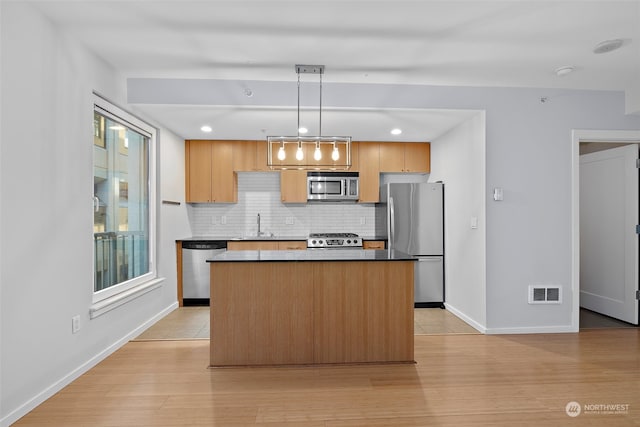 kitchen with decorative backsplash, stainless steel appliances, pendant lighting, light hardwood / wood-style floors, and a kitchen island