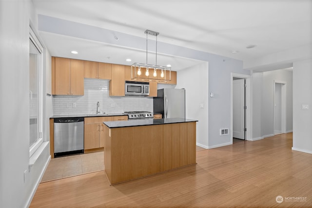 kitchen with a kitchen island, pendant lighting, decorative backsplash, appliances with stainless steel finishes, and light hardwood / wood-style floors